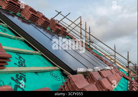 Couvreur installant des panneaux solaires sur un toit résidentiel Banque D'Images