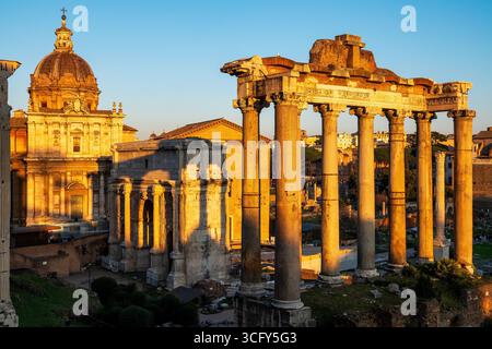Vue du Forum romain au coucher du soleil avec le Temple de Saturne, Arc de Septimius sévère et Santi Luca e Martina, Rome, Italie. Banque D'Images