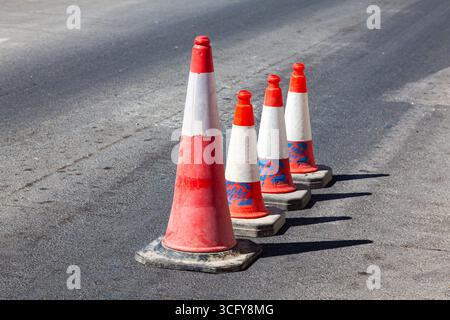 Des cônes de circulation se dressent dans une rangée sur une route asphaltée. Dispositifs pour le marquage temporaire de routes. Les cônes Avriynye se tiennent sur la route. Banque D'Images
