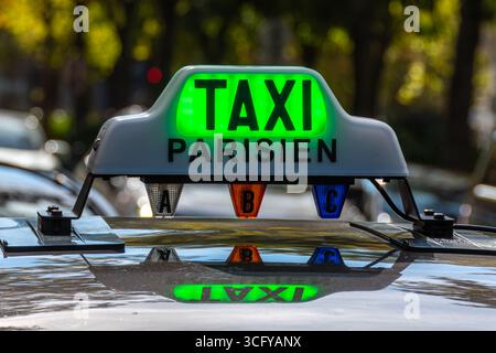Gros plan du panneau lumineux sur le toit d'un taxi parisien avec le mot « TAXI » allumé en vert (taxi gratuit) à une station de taxis dans une rue de Paris Banque D'Images