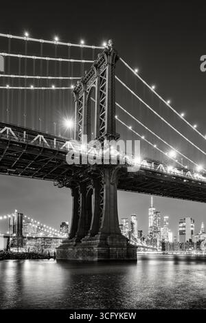 New York City vue nocturne en noir et blanc sur le pont de Manhattan depuis DUMBO. Gratte-ciel illuminé de Manhattan avec gratte-ciel et East River Banque D'Images