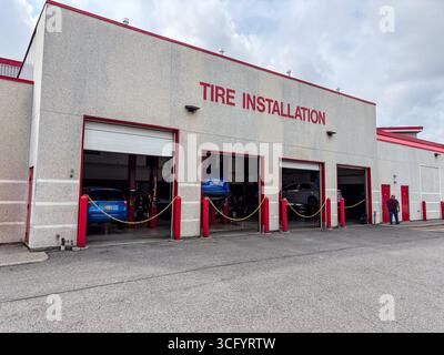 Centre d'installation de pneus Costco avec plusieurs aires de service ouvertes, montrant les voitures sur les ascenseurs en cours d'entretien. Vue extérieure d'un service automobile au détail de Banque D'Images