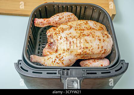 Morceaux de poulet crus dans une marinade naturelle de yaourt et curry, disposés sur un plateau avant la friture à l'air pour un maximum de jutosité Banque D'Images
