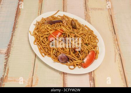 Nouilles péruviennes sautées à la vapeur avec poulet râpé, lanières de poivrons et coriandre fraîche, servies avec leur riz chaufa signature Banque D'Images