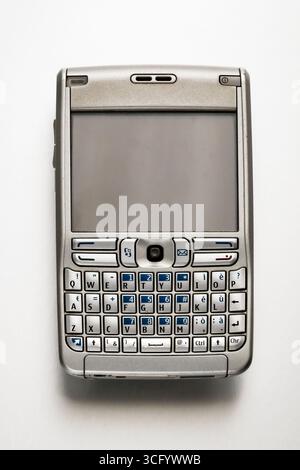 Vieux téléphone mobile avec clavier physique et écran blanc couché sur un fond blanc Banque D'Images