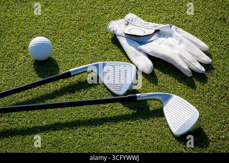 Clubs de golf, balle et gant sont couchés sur l'herbe verte d'un terrain de golf Banque D'Images