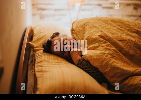 Femme âgée se reposant paisiblement dans un lit confortable tout en embrassant le calme Banque D'Images