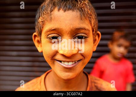 Portrait d'un enfant souriant avec des couleurs sur son visage, célébrant le festival holi, festival des couleurs dans les rues du quartier de mumbai en inde Banque D'Images