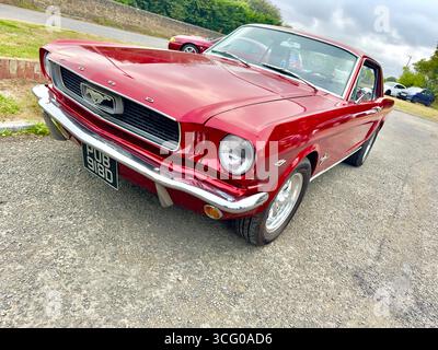 Classic Red 1966 Ford Mustang garé sur une route rurale avec ciel couvert en arrière-plan Banque D'Images