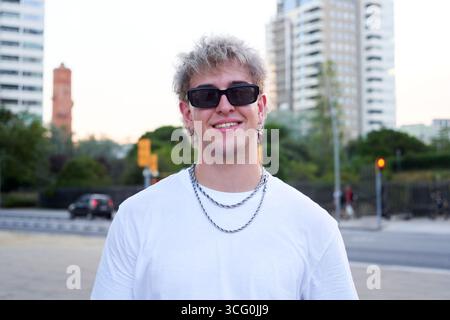 Portrait d'un jeune homme caucasien regardant la caméra souriant, debout dans une rue urbaine. Banque D'Images