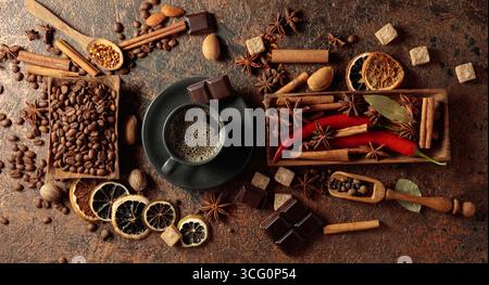 Diverses épices et assaisonnements pour faire des boissons aromatiques à base de café. Café noir dans une tasse noire. Vue de dessus. Banque D'Images