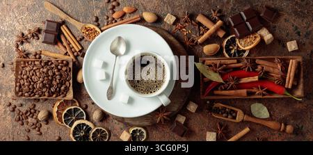 Diverses épices et assaisonnements pour faire des boissons aromatiques à base de café. Café noir dans une tasse blanche. Vue de dessus. Banque D'Images