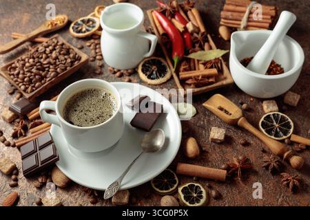 Diverses épices et assaisonnements pour faire des boissons aromatiques à base de café. Café noir dans une tasse blanche. Banque D'Images