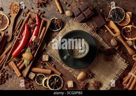 Diverses épices et assaisonnements pour faire des boissons aromatiques à base de café. Café noir dans une tasse noire. Vue de dessus. Banque D'Images