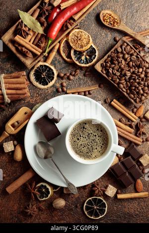 Diverses épices et assaisonnements pour faire des boissons aromatiques à base de café. Café noir dans une tasse blanche. Vue de dessus. Banque D'Images