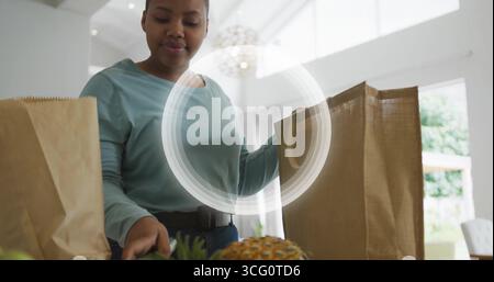 Déballage femme portant le dessus sarcelle déchargement de l'épicerie à l'île de marbre, ananas et verts feuillus Banque D'Images