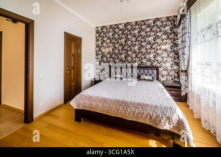 Une chambre avec un lit, commode et une fenêtre. Le lit est recouvert d'un drap blanc et d'une couette blanche. La chambre a une atmosphère chaleureuse et accueillante Banque D'Images