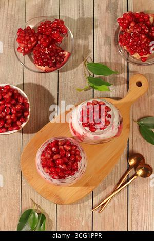 Yaourt aux fruits avec des graines de grenade et de la crème de vache fraîche pour une nutrition saine dans un verre sur une table élégante. Petit déjeuner sain avec des ingrédients, Kitc Banque D'Images