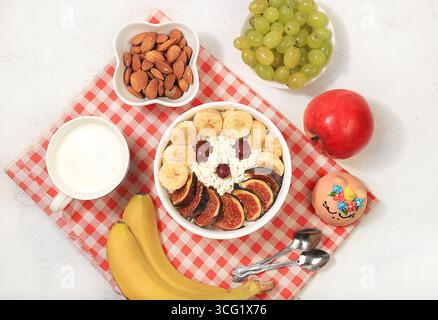 Petit déjeuner sain avec des ingrédients, nourriture amusante pour les enfants. Le concept de nourriture saine et naturelle. Fromage cottage avec figues et bananes, noix et raisins, Banque D'Images