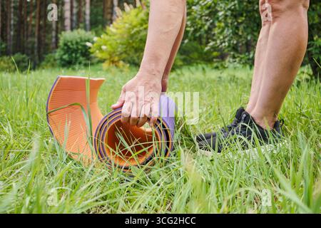 Femme mature se préparant à l'exercice et à la pose de tapis au parc public de près Banque D'Images