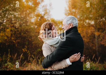 Promenade romantique à travers la forêt d'automne par couple senior. Banque D'Images
