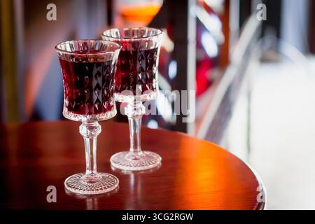 Deux verres de baies alcoolisées rouges et de liqueur de cerise se tiennent sur une table en bois à l'intérieur du restaurant. Copier l'espace Banque D'Images