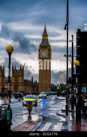 Vue emblématique de la tour de l'horloge Big Ben à Westminster avec la circulation, les voitures de police et les piétons sur une rue pluvieuse de Londres sous des nuages spectaculaires Banque D'Images