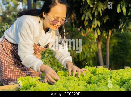 Une femme asiatique âgée travaillant dans le jardin et plantant des graines dans son jardin animé. Banque D'Images