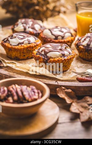 Muffins aux carottes aux noix, glacés avec fromage à la crème et chocolat et jus de carotte Banque D'Images