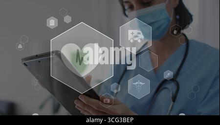 Infirmière portant des gommages et stéthoscope tenant la tablette interagissant avec les icônes dans l'hôpital, espace de copie Banque D'Images