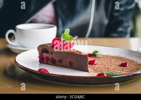 Une tasse de café avec un gâteau au brownie au chocolat avec des cerises et de la menthe. Dessert doux ?hocolate dans un café. Recettes de bonbons maison Banque D'Images