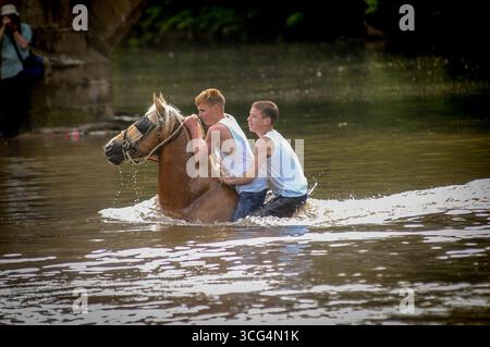 Deux jeunes hommes montent à cheval dans la rivière Eden à Appleby Horse Fair dans le Cumbria, Royaume-Uni. Banque D'Images