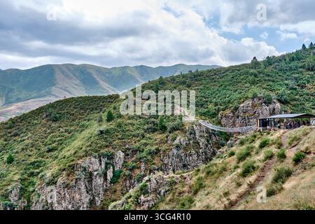 Kirghizistan, Bichkek - 11 juillet 2025 : vue panoramique du pont suspendu enjambant la gorge rocheuse Chunkurchak, Kirghizistan, entouré de collines verdoyantes et Banque D'Images