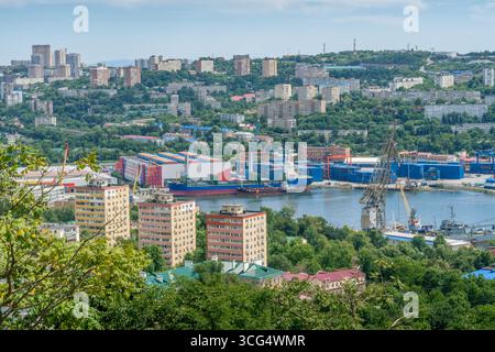 Vue panoramique sur la baie de la Corne d'Or de Vladivostok, présentant le port animé de la ville, les grues industrielles et l'infrastructure commerciale maritime en Russie Banque D'Images