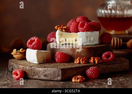 Camembert avec framboises fraîches et noix sur une table vintage brune. Banque D'Images