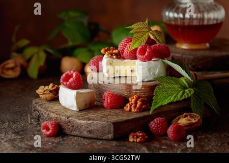Camembert avec framboises fraîches et noix sur une table vintage brune. Banque D'Images