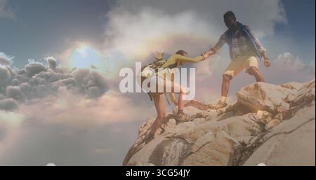 Couple d'escalade dans le matériel de randonnée s'aidant l'un l'autre au sommet de la montagne, avec sacs à dos et bouteille d'eau Banque D'Images