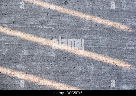 Les ombres tombent en diagonale sur une surface de béton texturée. Banque D'Images