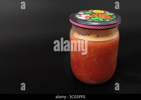 Gros plan du pot en verre avec de la sauce tomate gâtée recouverte de moisissure sur fond noir concept de gaspillage alimentaire malsain et conservation gâtée Banque D'Images
