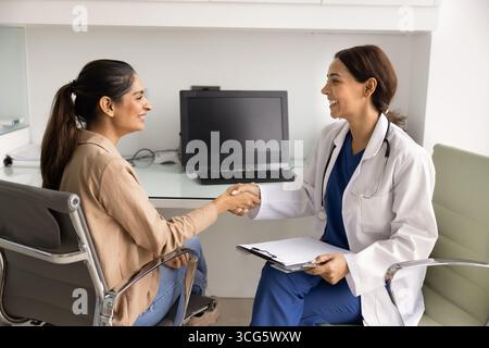 Patiente heureuse et doc serrant la main au cabinet clinique Banque D'Images