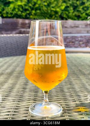 Verre de bière blonde dorée sur une table dans le jardin arrière d'une maison. Personne. Banque D'Images