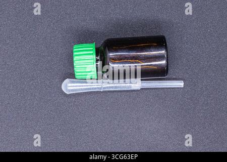 Flacon en verre ambré avec bouchon vert et pipette transparente, idéal pour la distribution d'huiles essentielles, de sérums ou de liquides. Parfait pour les soins de la peau, aromathérapie. Banque D'Images