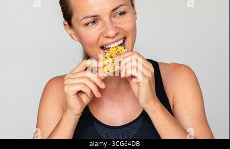 Ajuster femelle mangeant des protéines barre de granola gros plan photo Banque D'Images