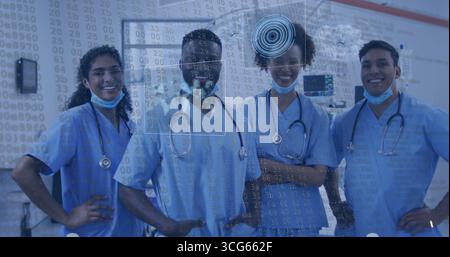 Équipe médicale souriante portant des gommages bleus, des masques et des stéthoscopes debout dans le service avec superposition de données Banque D'Images