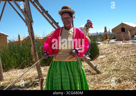 Îles Uros, Pérou - 16/2012 : une femme indigène Uros sur les îles flottantes du lac Titicaca au Pérou portant des vêtements traditionnels avec un bowling Banque D'Images