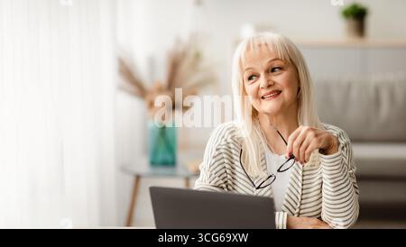 Femme d'âge mûr assise au bureau avec ordinateur Banque D'Images