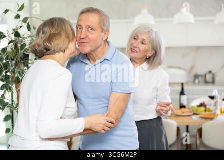 Deux couples de personnes âgées se accueillent chaleureusement alors qu'ils se réunissent pour un dîner festif de vacances à la maison Banque D'Images