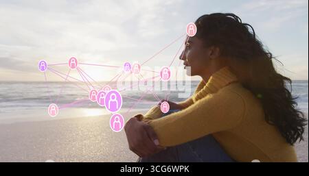 Femme assise portant un pull, jeans sur le rivage au coucher du soleil avec des vagues, icônes de réseau, espace de copie Banque D'Images