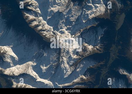 Le soleil se reflète sur les sommets enneigés des Alpes suisses tout en projetant des ombres sur les contreforts de la chaîne de montagnes alors que la Station spatiale internationale orbite à 260 miles au-dessus de la Suisse. 25 septembre 2023 une version optimisée d'une image originale de la NASA : crédit NASA/AMogensen Banque D'Images
