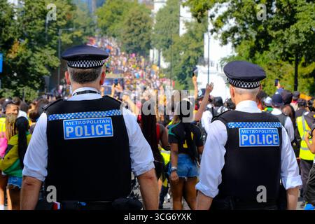 Deux policiers patrouillant observent la foule à Ladbroke Grove pendant le carnaval de Notting Hill alors que 7 000 policiers sont déployés. Banque D'Images